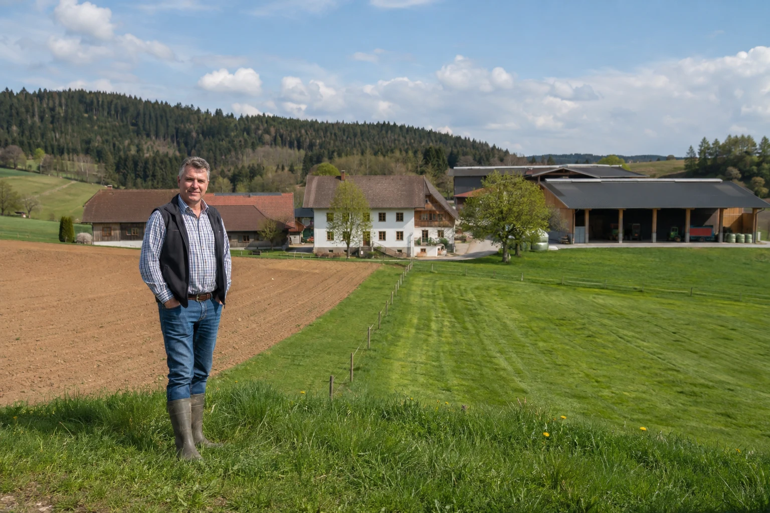 Landwirt vor Flächen, Hofstelle und Wirtschaftsgebäuden eines Agrarbetriebes